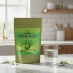Glass of herbal water next to Neem Giloy pouch on marble